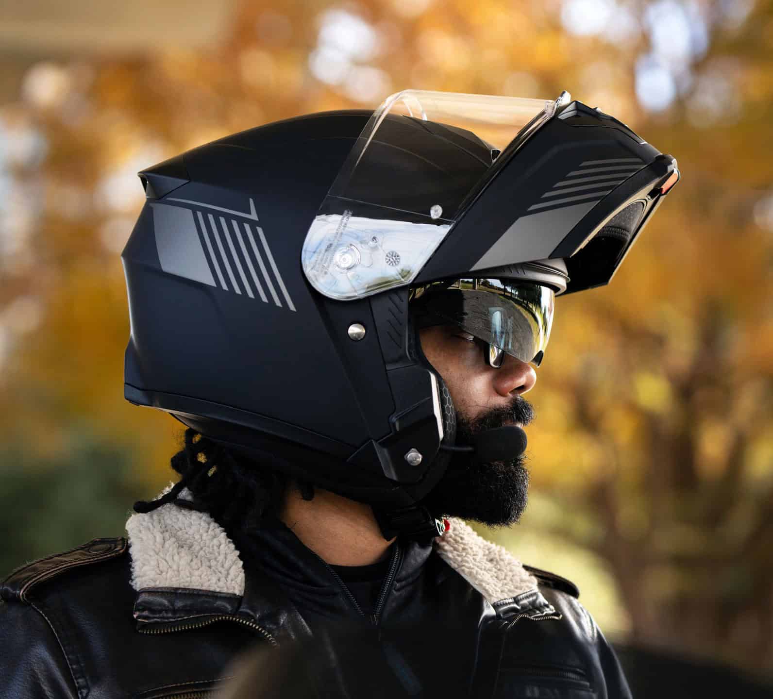 Rider wearing Sena Specter modular helmet with visor up and built-in intercom system
