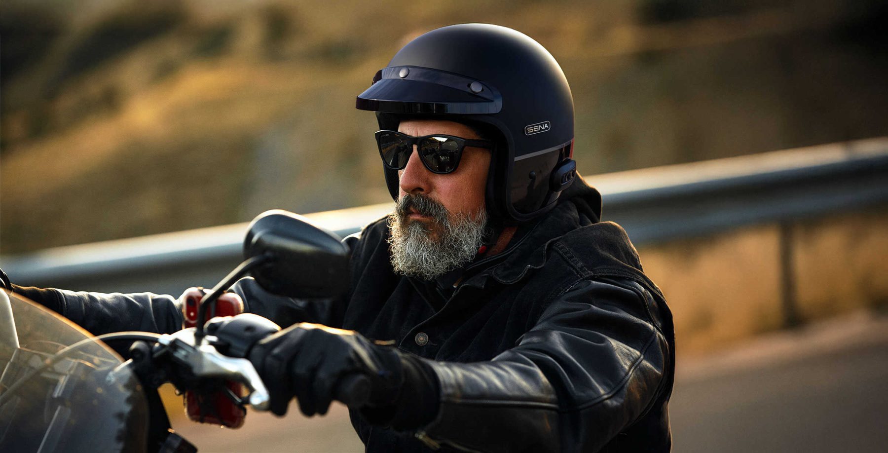 Rider wearing a Sena Surge open-face helmet with built-in communication while cruising on the road