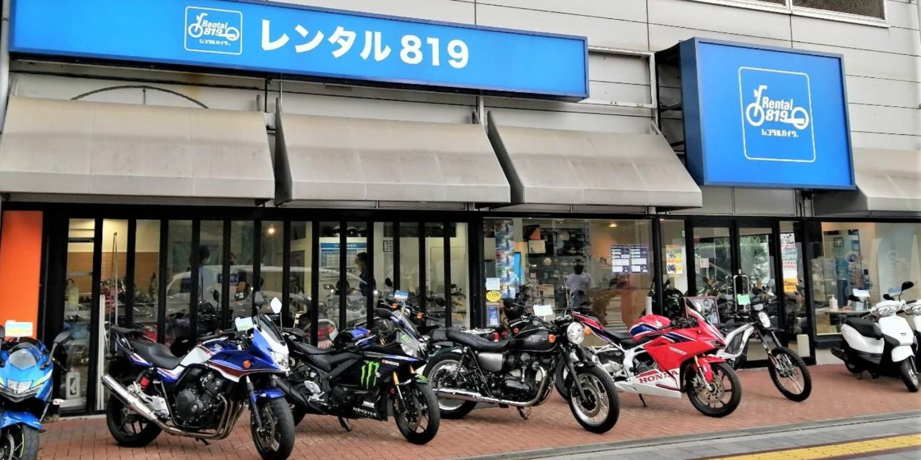 The front of a rental shop with several motorcycles parked in front. 