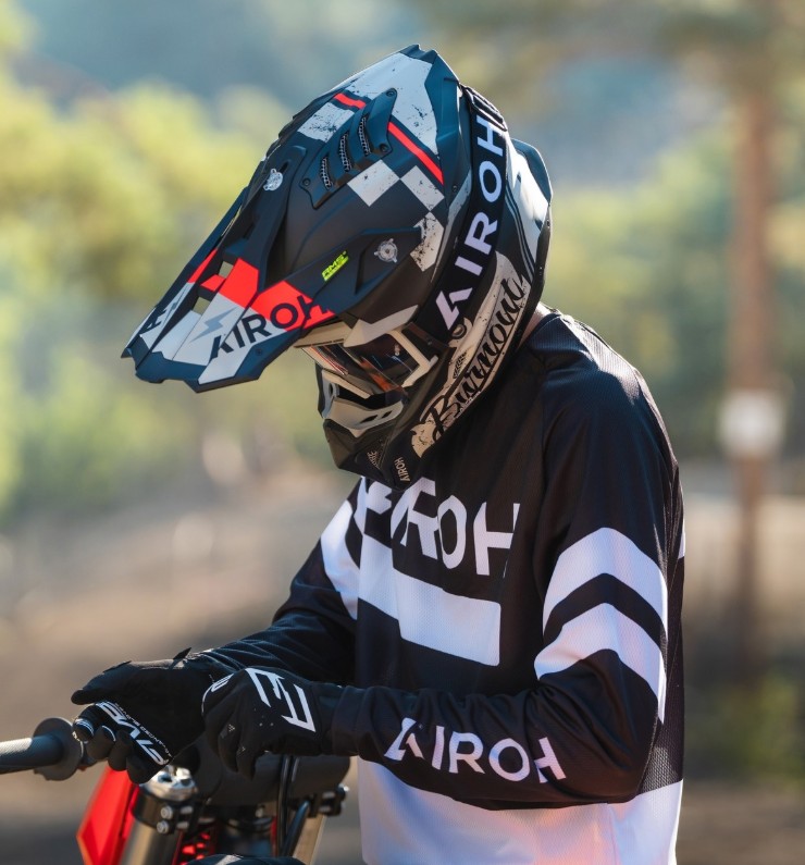 Rider wearing Airoh Aviator 3 carbon motocross helmet while sitting on a dirt bike outdoors