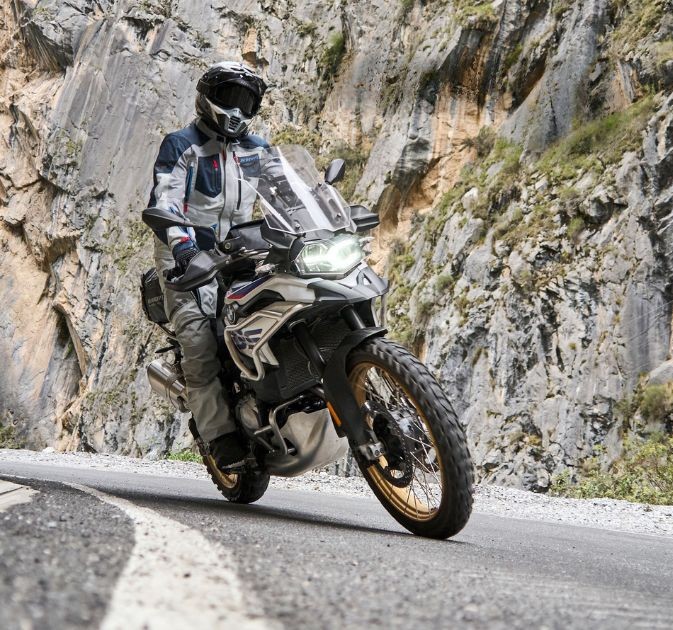 Adventure rider wearing Klim Carlsbad Pants navigating a mountain road on a dual-sport bike.