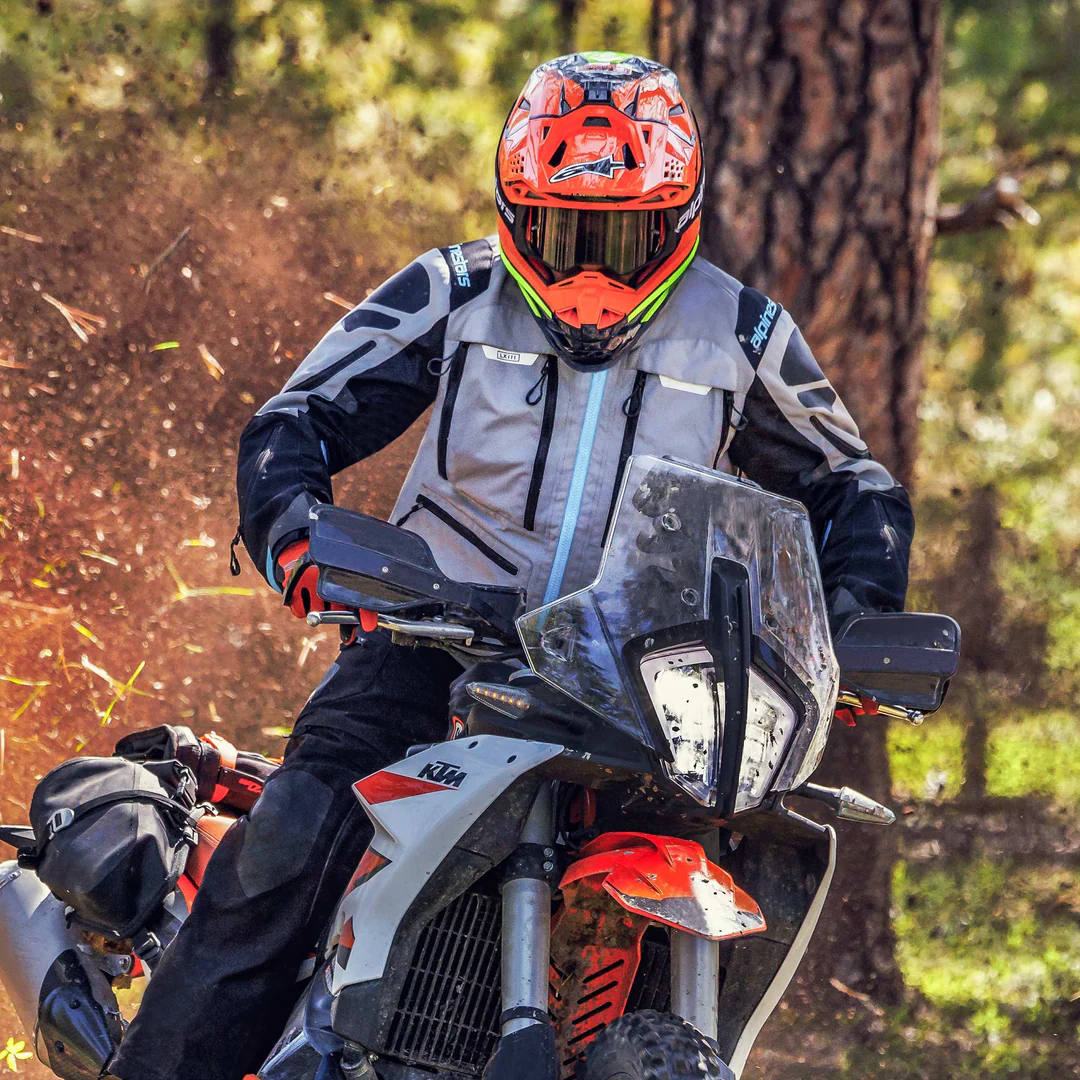 Rider wearing the Alpinestars Ardent 3in1 jacket on a KTM adventure bike kicking up trail dust