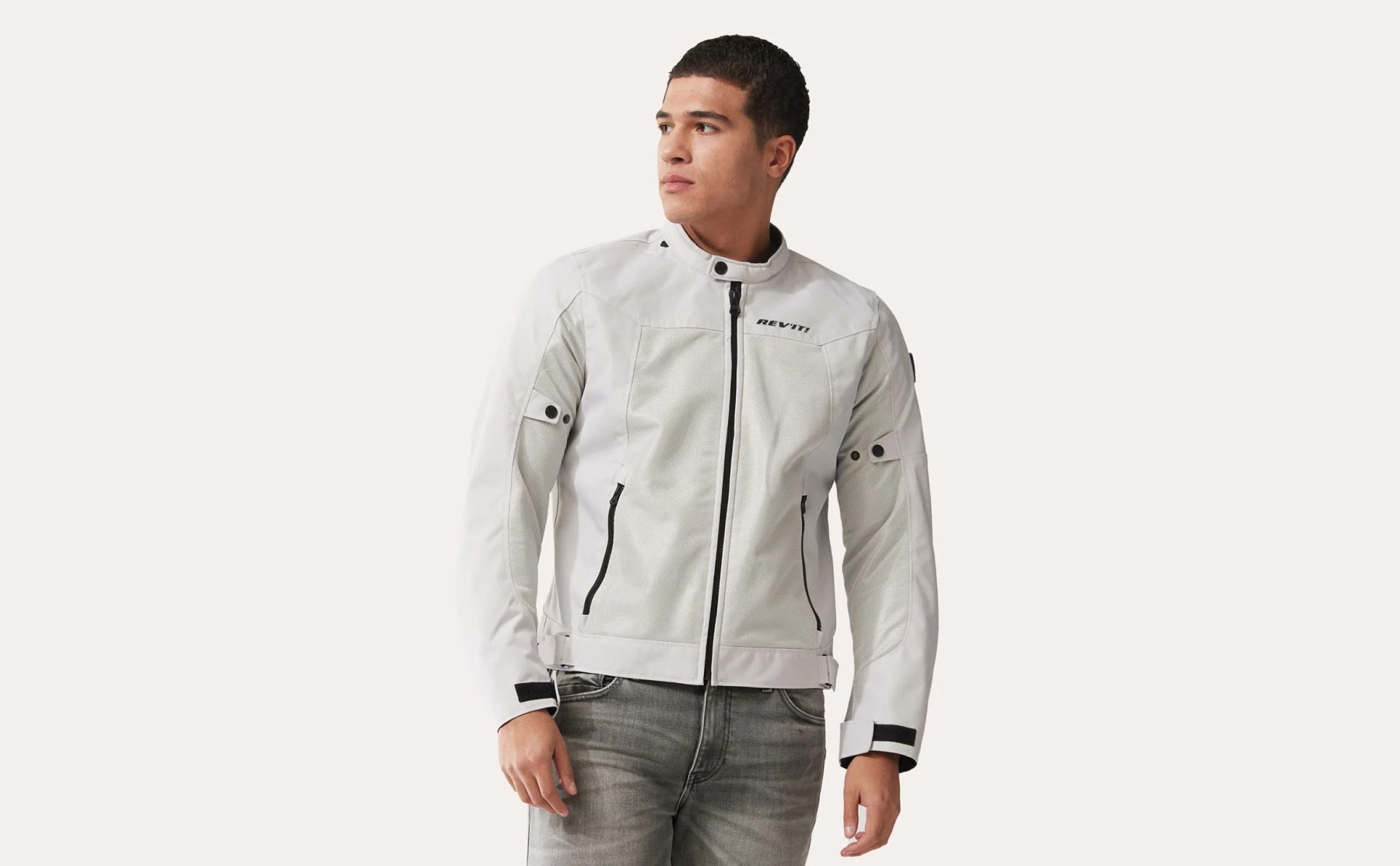 Man wearing a light-colored REV'IT! Eclipse 2 mesh motorcycle jacket, standing in a neutral studio setting