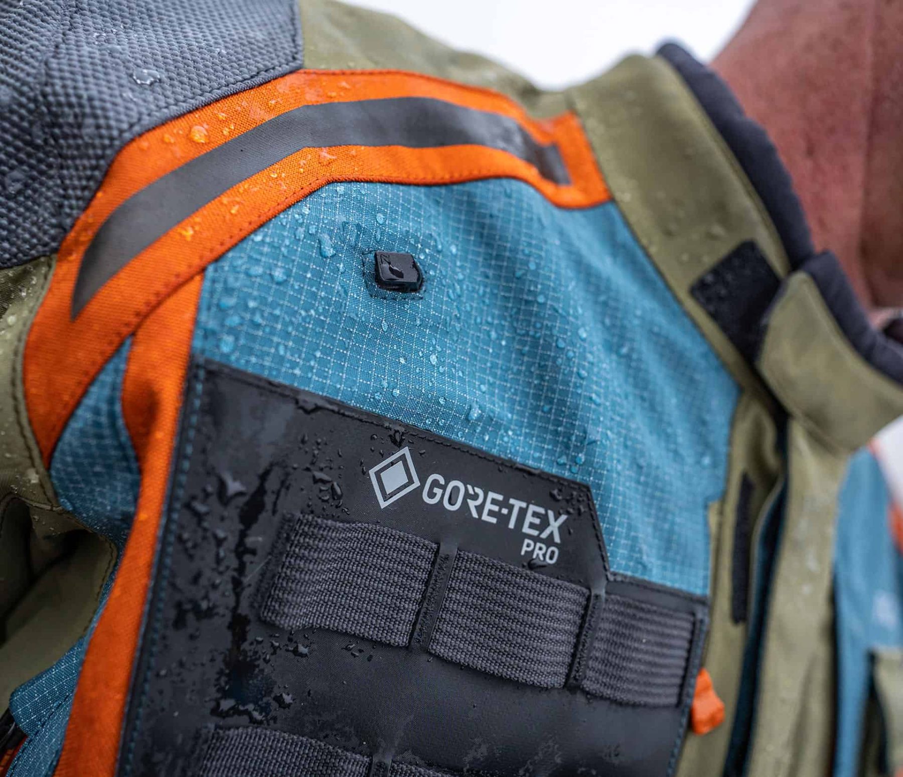 Close-up of a Gore-Tex Pro motorcycle jacket with water beading on the laminated shell in the rain