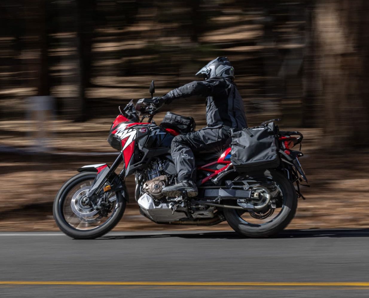 Adventure rider in full Klim Badlands Pro A3 gear riding through forested terrain