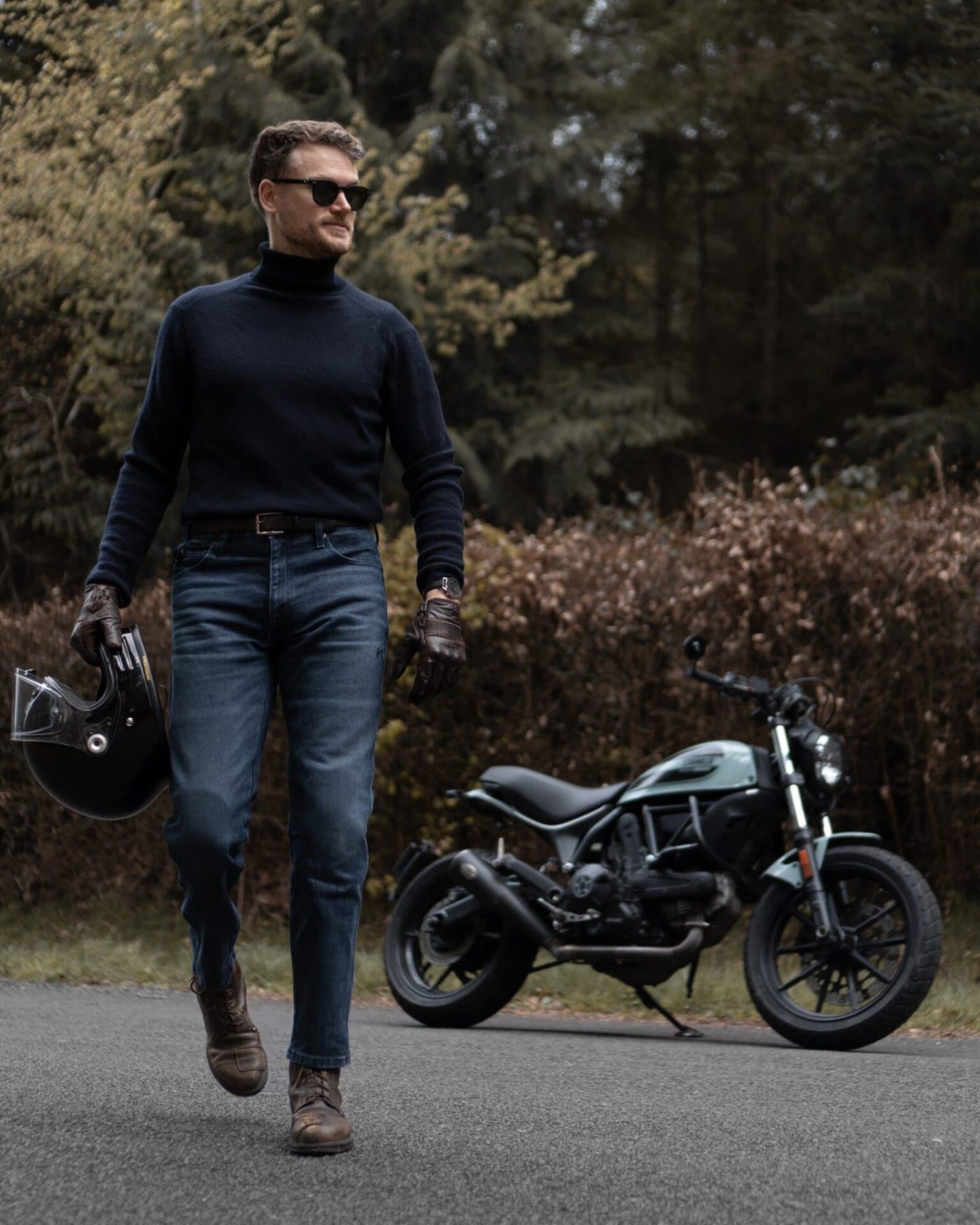 Man walking in motorcycle jeans and holding helmet, Pando Moto Arnie Slim in action