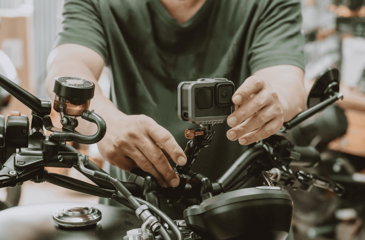 Person installing an action camera on a motorcycle handlebar using a handlebar mount