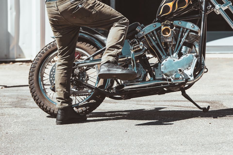 Motorcyclist wearing Highway 21 Axle Shoes while kickstarting a vintage cruiser motorcycle