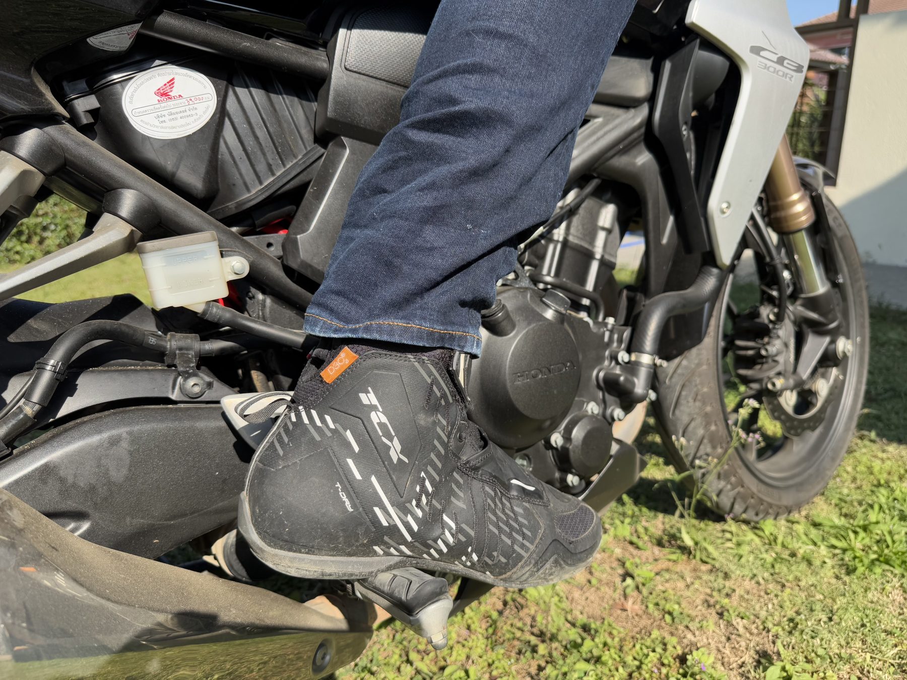 Close-up of TCX R04D WP riding shoes worn by a motorcyclist, showcasing the shoe's protective and sporty design.