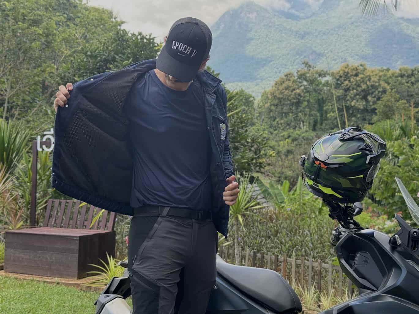 Motorcyclist showing a snug motorcycle jacket fit with thin base layer while standing beside a parked bike