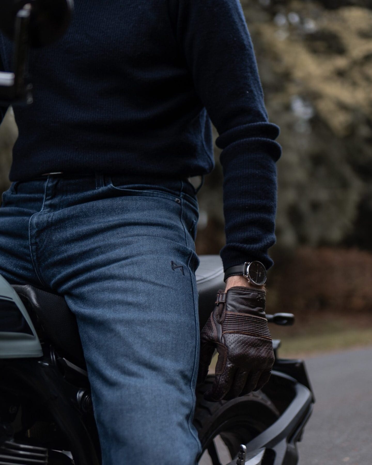 Close-up of rider wearing Pando Moto Arnie Slim CE AAA-rated jeans while seated on a motorcycle, showcasing clean fit and understated style
