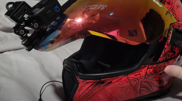 Close-up of an Icon Airflite helmet with GoPro mounted and face shield slightly raised, showing chin vent and internal visor setup