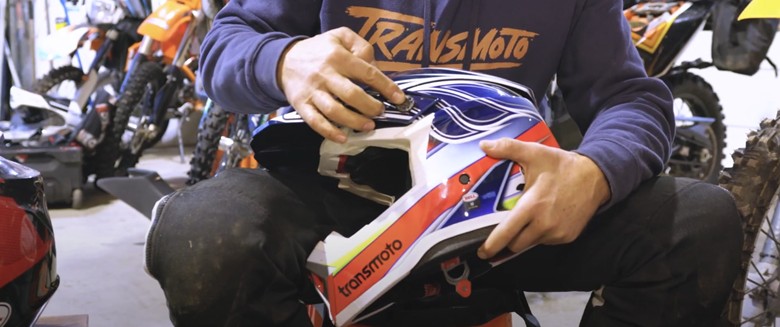 Person adjusting the visor screw on a Bell Moto-10 helmet in a garage setting