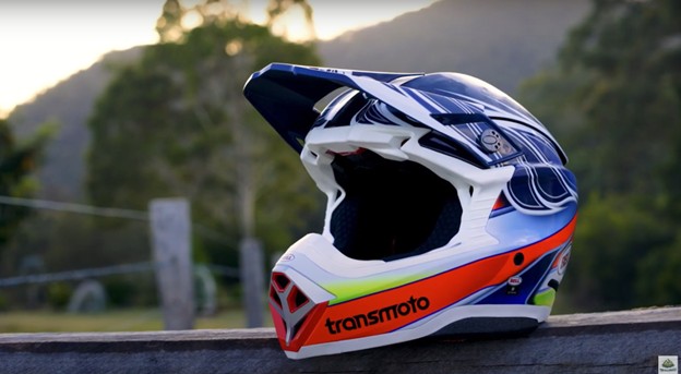 Bell Moto-10 helmet resting on a wooden fence with scenic trees in the background