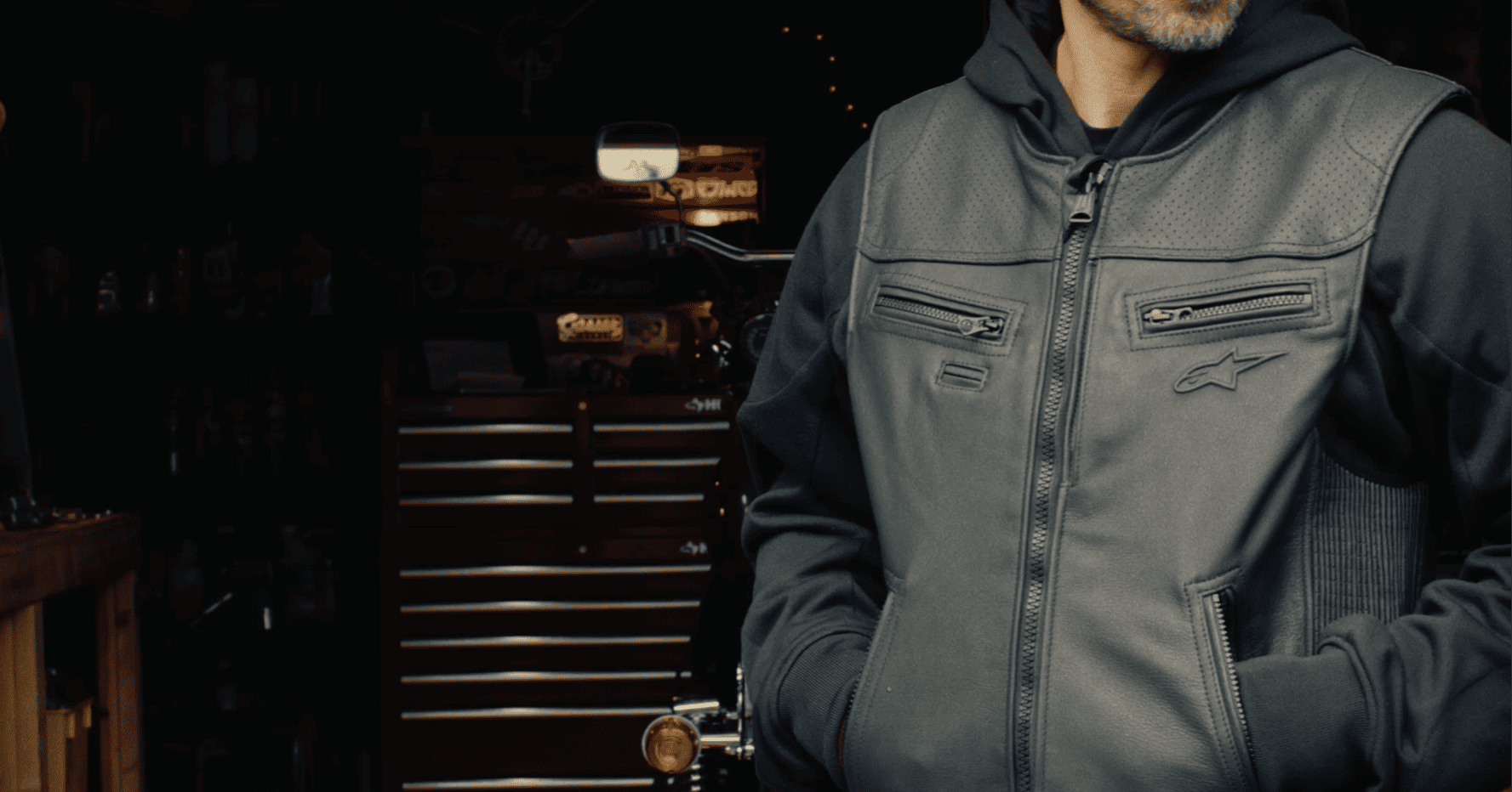 Close-up of a rider wearing an Alpinestars leather airbag vest in a garage