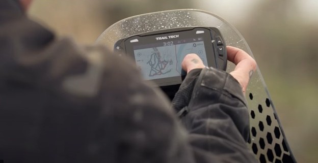Rider using Trail Tech Voyager Pro GPS on a rugged terrain with glove-friendly touchscreen