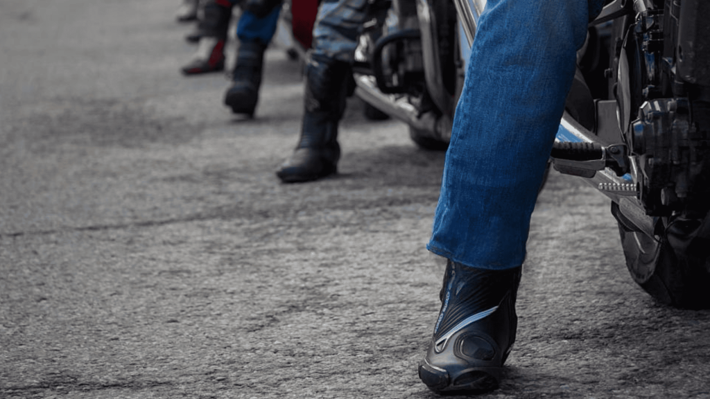 Motorcyclists wearing protective riding boots, showing different styles lined up on a city street.