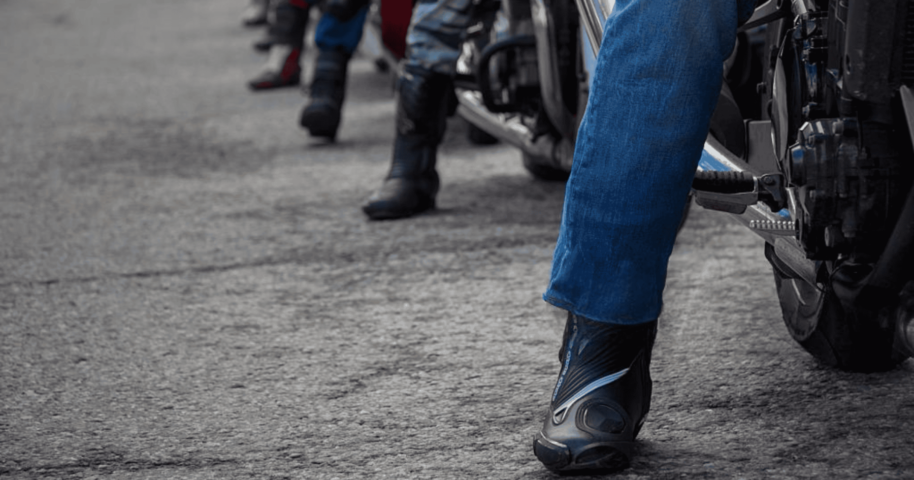 Motorcyclists wearing protective riding boots, showing different styles lined up on a city street.