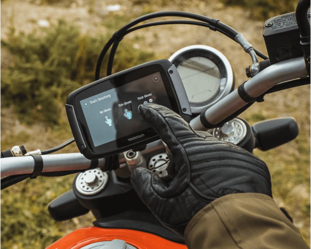 Motorcyclist adjusting glove sensitivity settings on TomTom Rider 550 GPS touchscreen