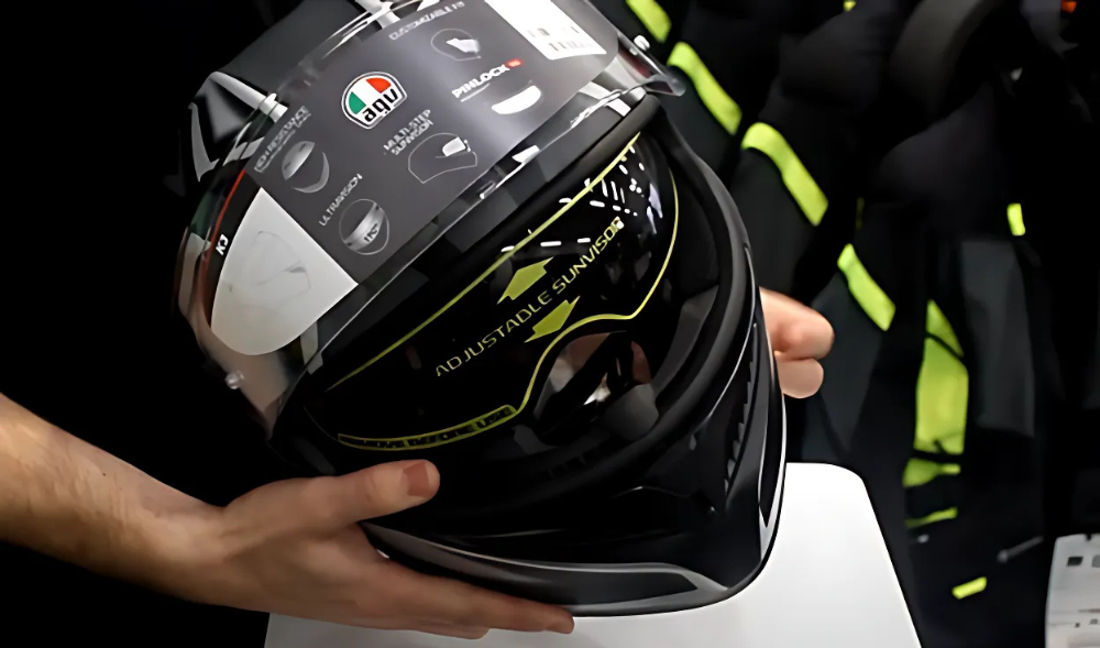 Hands holding an AGV K3 helmet showing the upgraded internal sun visor