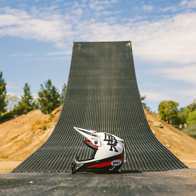 Bell MX-9 helmet resting at the base of a dirt ramp in an off-road setting