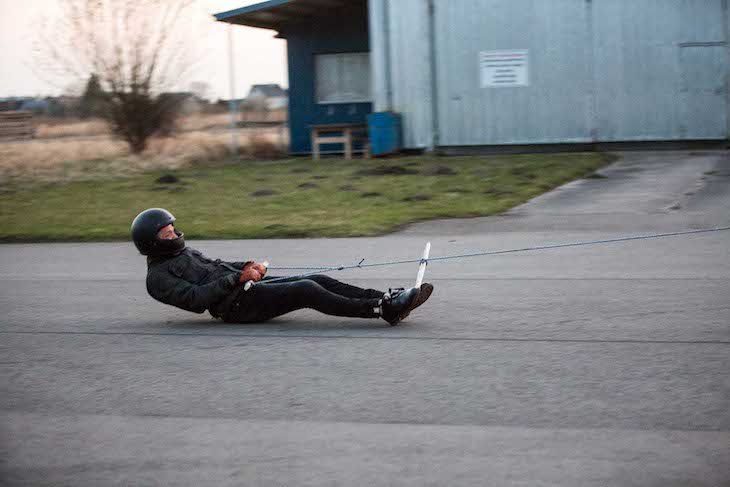 Abrasion resistance test with rider being dragged on asphalt in motorcycle jeans