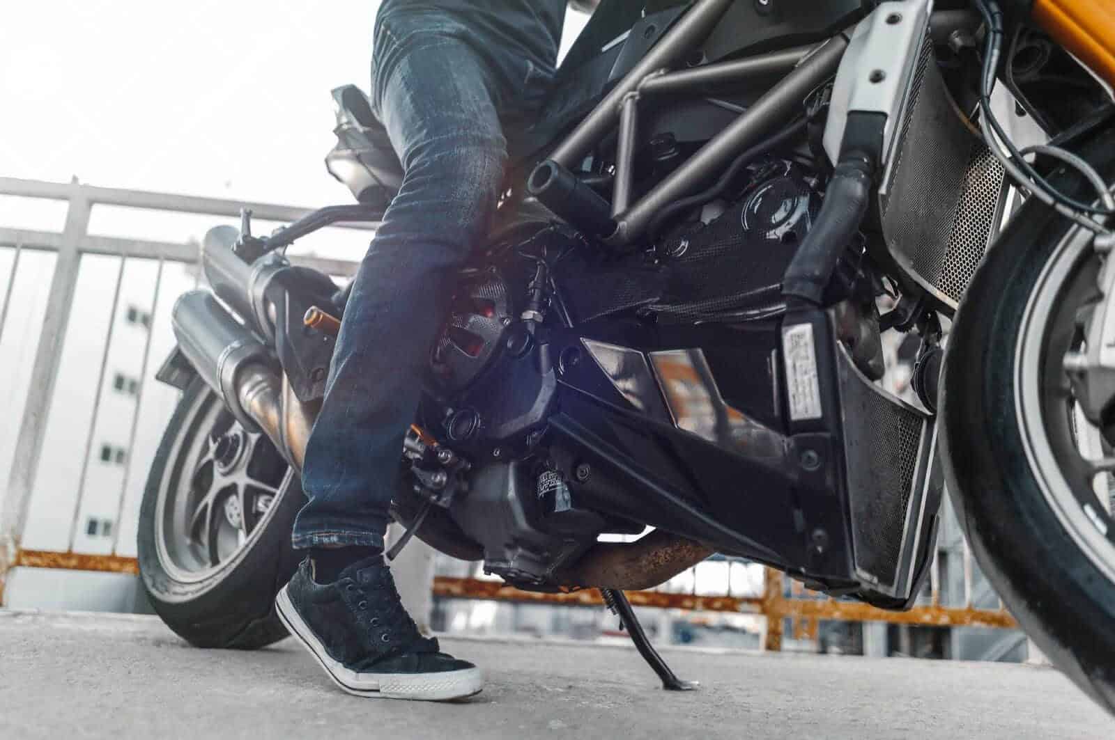 Motorcyclist wearing casual sneakers while sitting on a parked bike