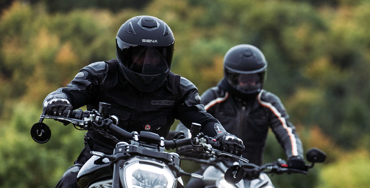 Two riders wearing full-face motorcycle helmets, including the Sena Stryker