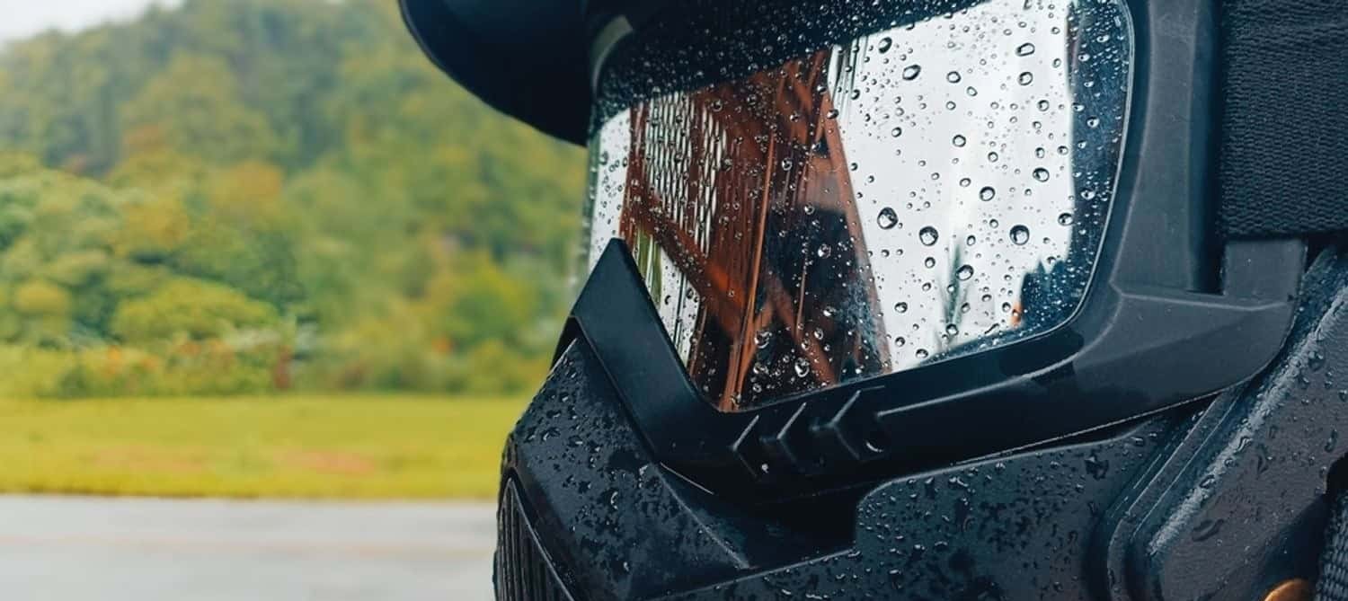 Close-up of a rain-covered motorcycle helmet and visor with water droplets