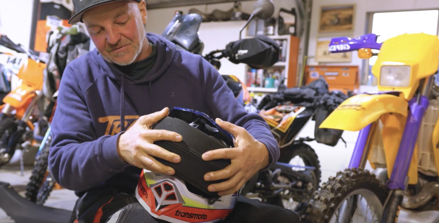 Rider placing a goggle hard case under the visor of a Bell Moto-10 helmet for protection