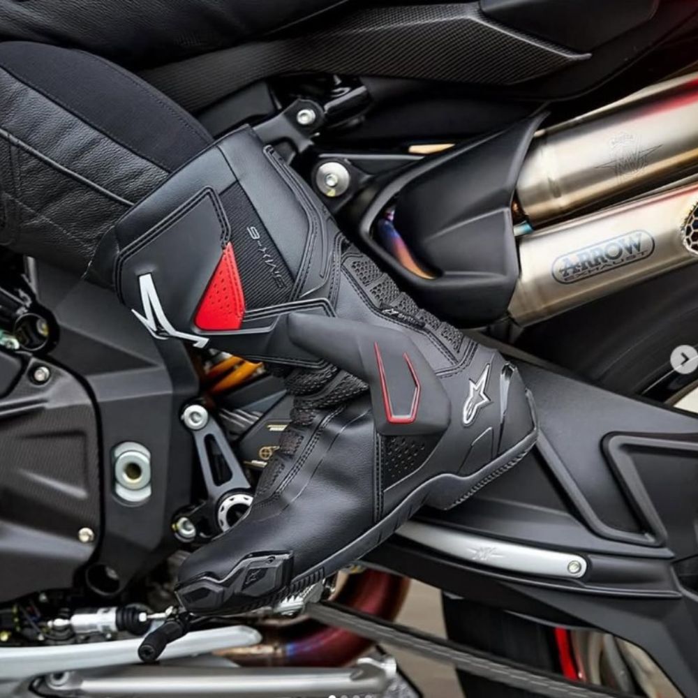 Close-up of a rider’s foot in black Alpinestars SMX-6 V3 vented boots on a sportbike footpeg, showing premium protection and airflow design