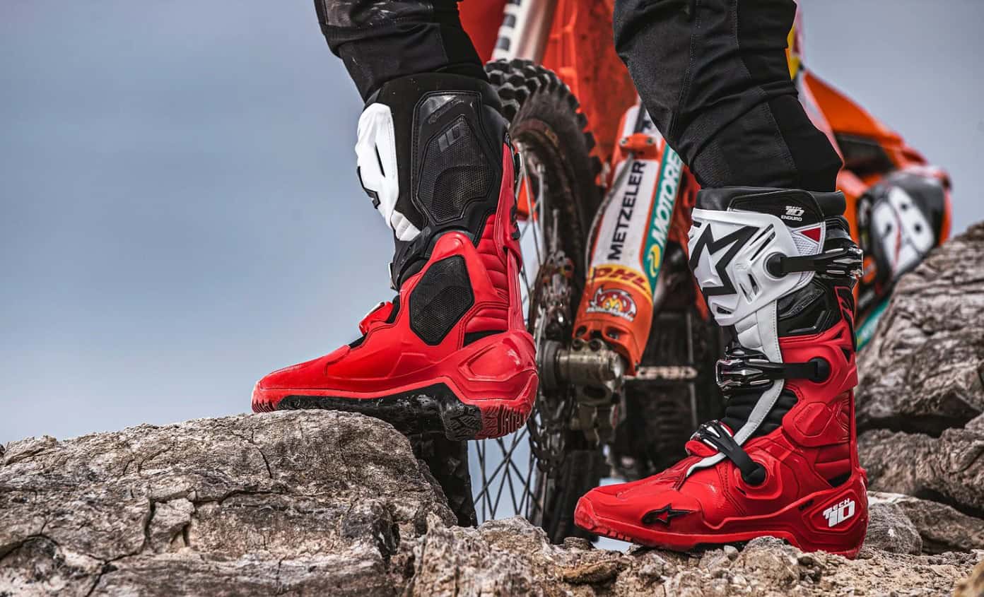 Close-up of Alpinestars Tech 10 Enduro boots on rocky terrain, showing lugged sole design and reinforced chassis for off-road performance.