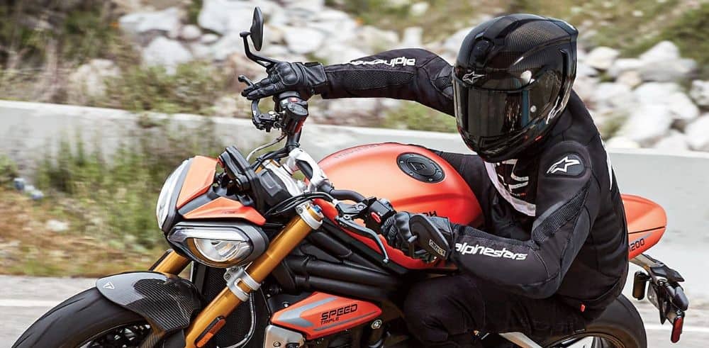 Sport rider wearing full Alpinestars gear cornering aggressively on a naked bike