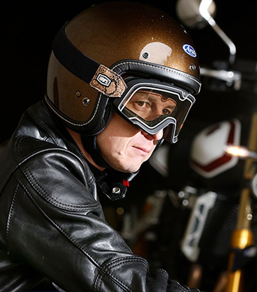 Close-up of a rider wearing an open-face Arai helmet and goggles with a leather jacket, ready for a summer urban ride