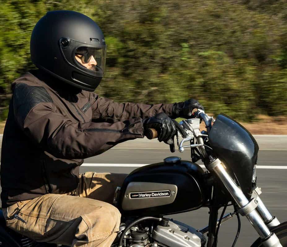 Rider wearing a matte black full-face helmet on a Harley-Davidson motorcycle