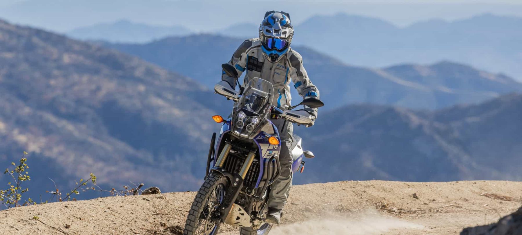 Adventure motorcyclist in full Klim gear riding a dual-sport bike off-road in the mountains