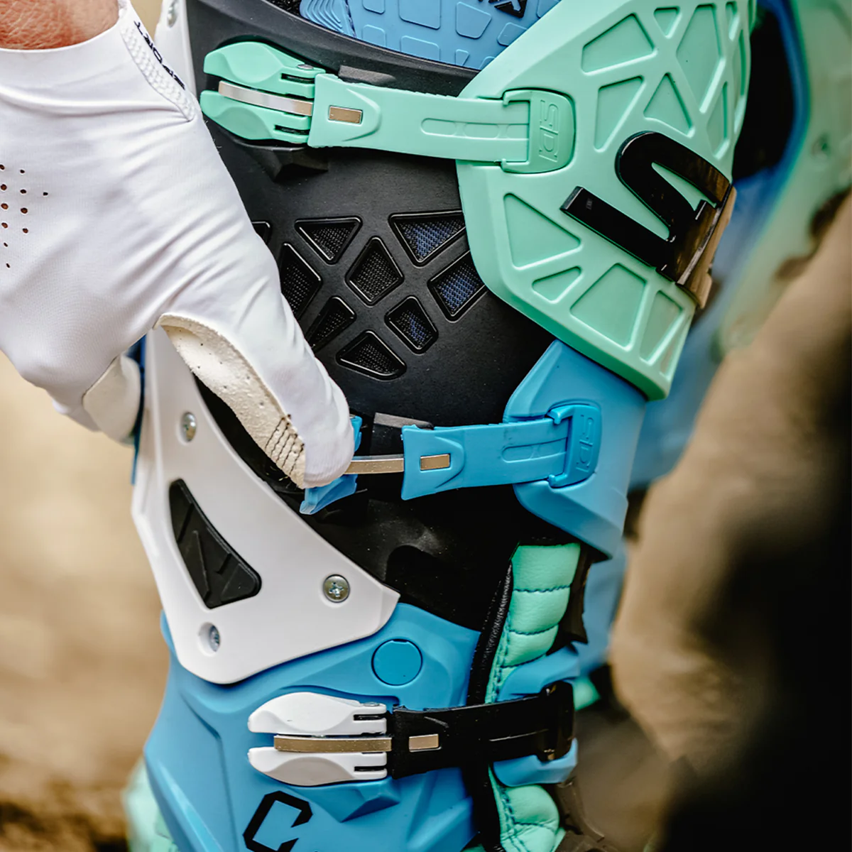 Close-up of a motocross rider adjusting a durable, glove-friendly buckle on a protective off-road boot