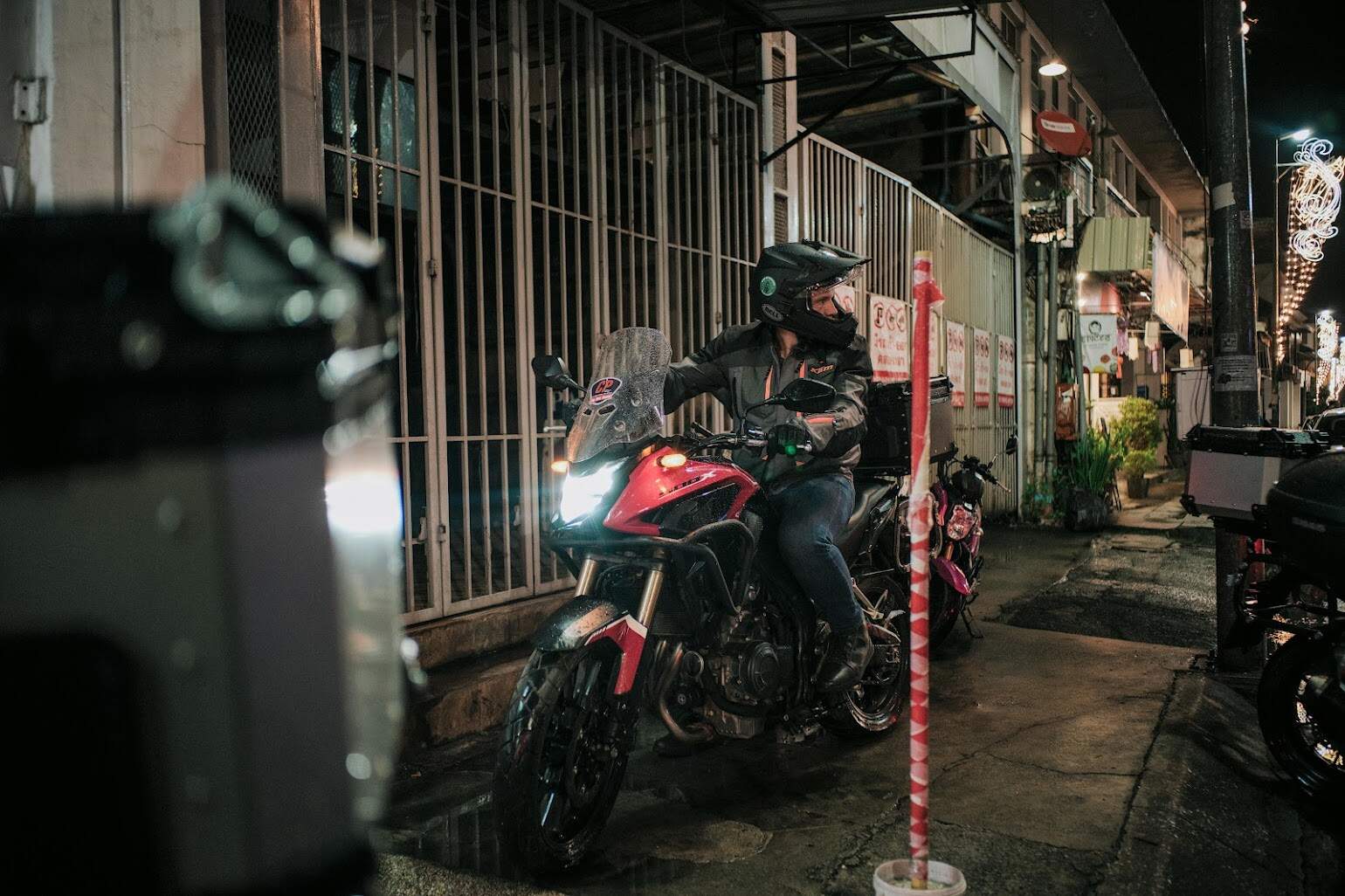 Motorcyclist in full gear riding through a wet alleyway at night
