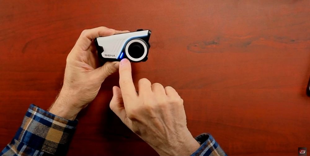 Close-up of a hand pointing to the Sena 60S jog dial and LED indicator