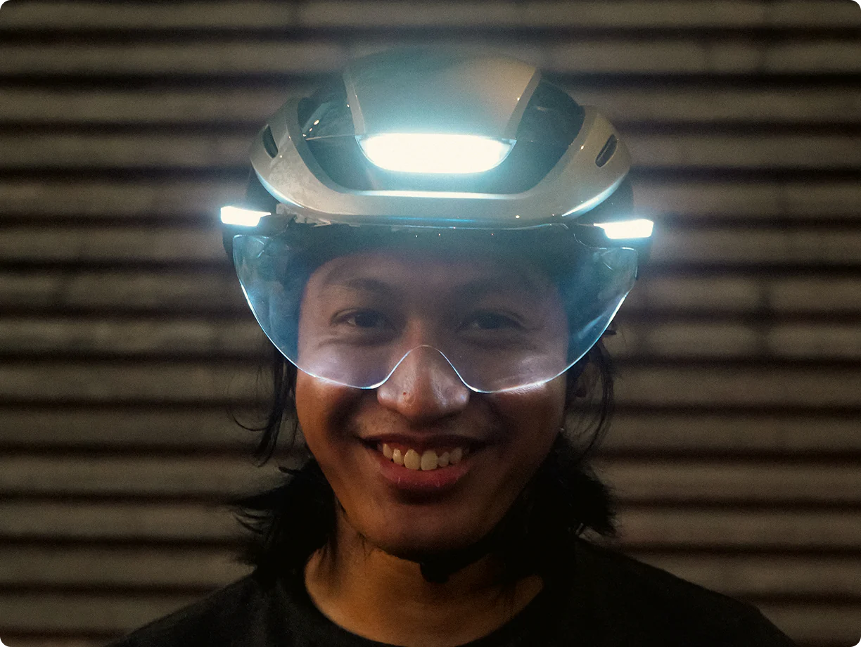 Rider wearing Lumos Ultra E-Bike Helmet with visor and bright LED lights activated
