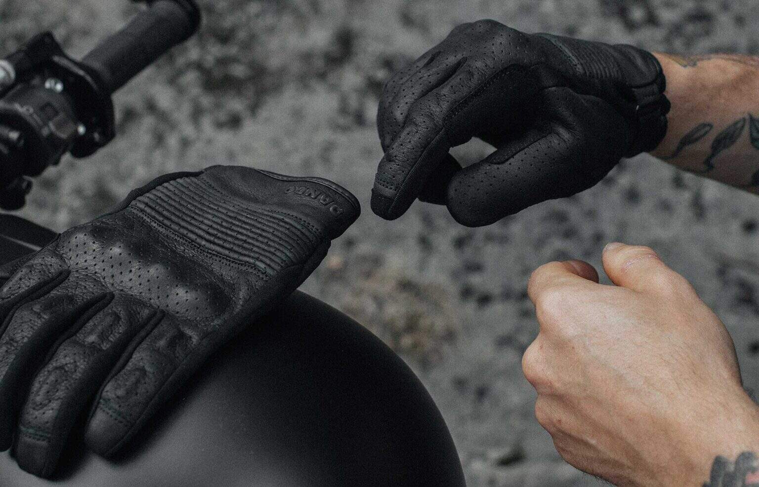 Close-up of a rider adjusting Pando Moto Onyx gloves with perforated leather and low-profile knuckle armor.