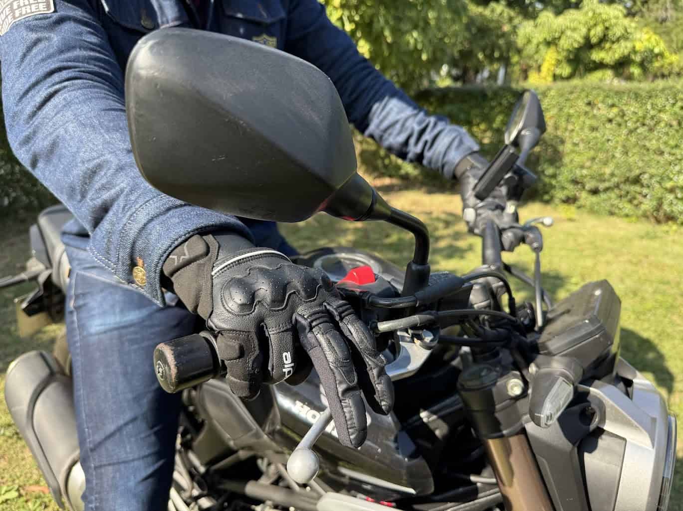 Rider wearing leather motorcycle gloves on a black bike, showing hand position on handlebar