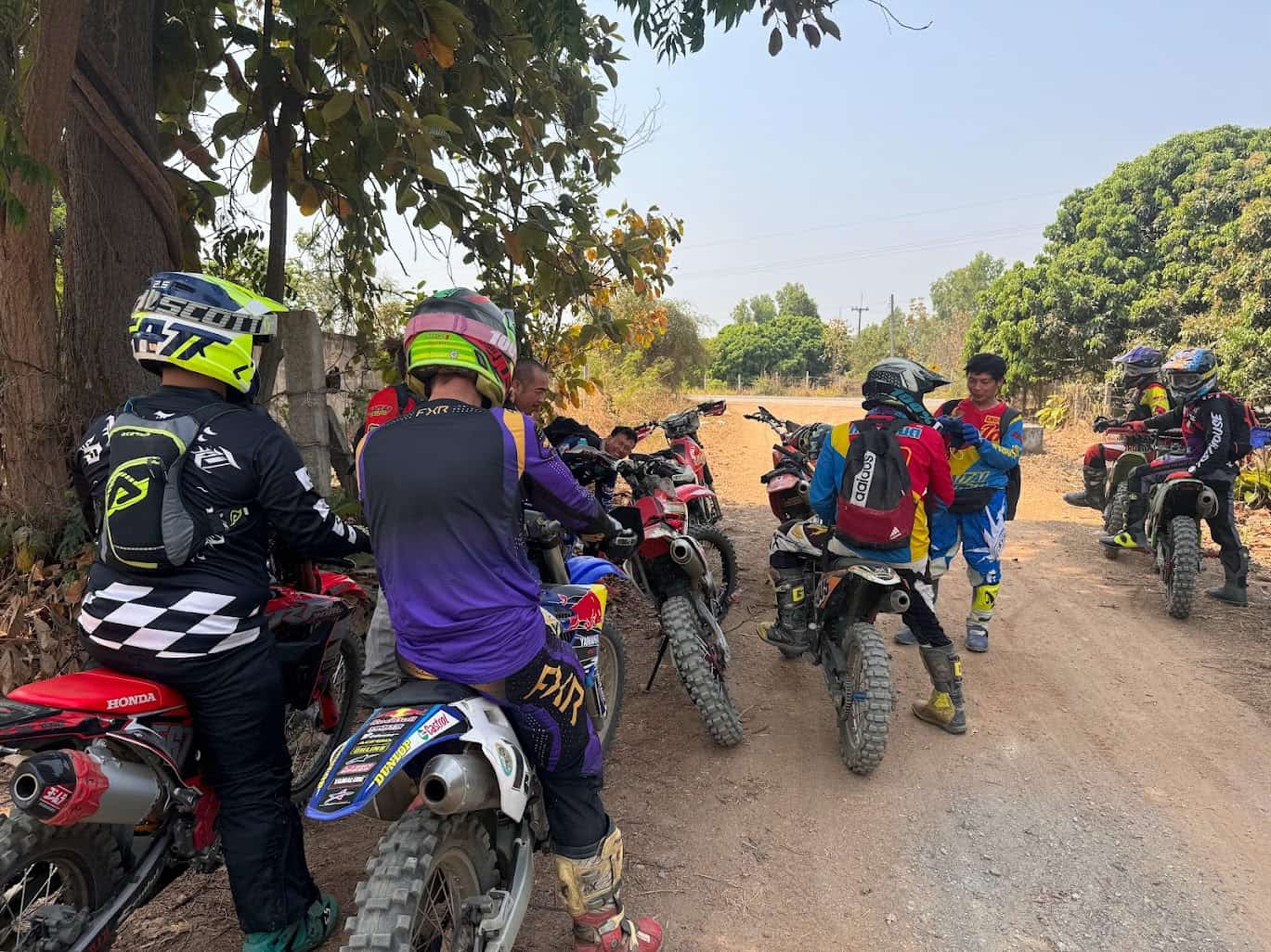 Group of dual-sport riders on dirt bikes taking a break on a trail
