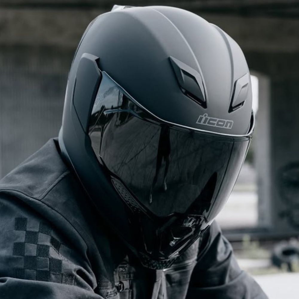 Rider wearing Icon Airflite helmet with smoked shield and bold styling
