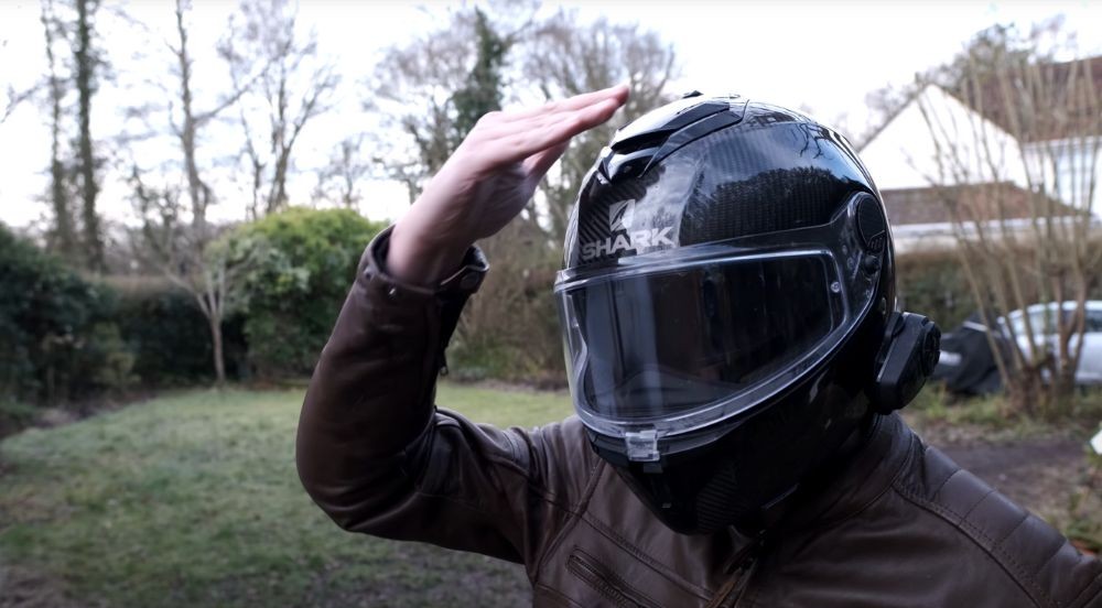 Rider using the top slider on the Shark Spartan GT Carbon to activate the internal sun visor