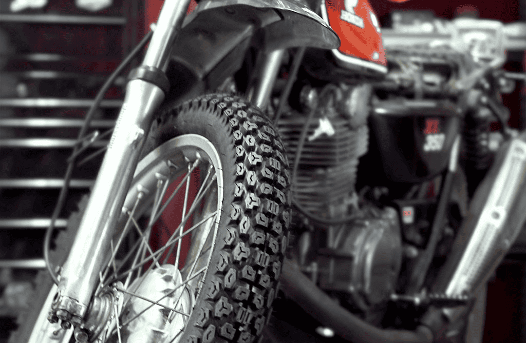 Close-up of a dual-sport motorcycle tire with knobby tread, designed for both street and light off-road use