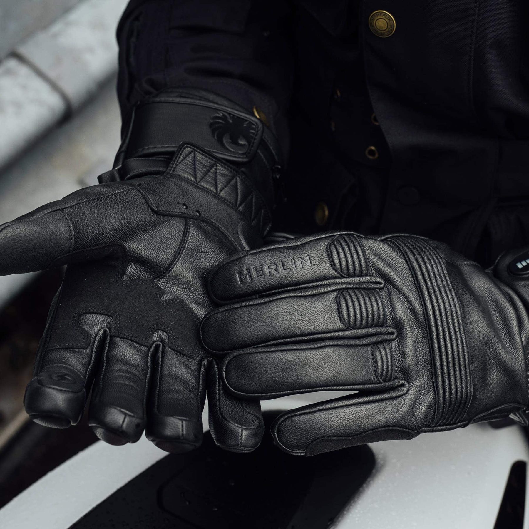 Rider wearing black Merlin Minworth II D3O Heated Gloves with visible leather construction and knuckle padding