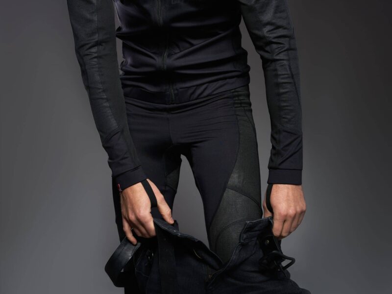 Close-up of a rider wearing Pando Moto armored base layers, pulling on a pair of jeans
