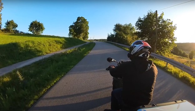 Motorcycle rider on a scenic road, used to illustrate Sena 50C mic performance in motovlogging