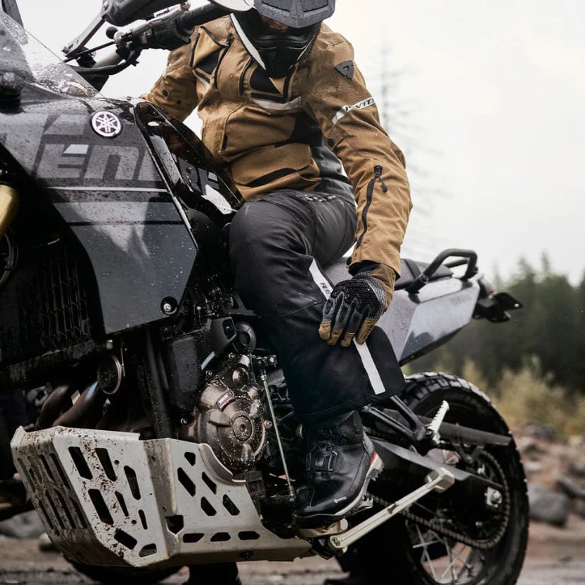 Rider on an adventure bike wearing REV’IT! Discovery GTX boots in wet, muddy conditions